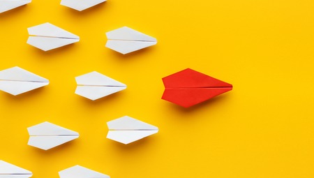 Opinion leadership. Red paper plane leading another colorful ones, influencing the crowd, yellow background, panoramaの写真素材