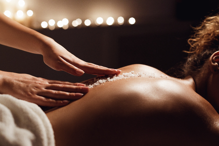African-american woman getting salt scrub treatment in health spa, closeupの写真素材