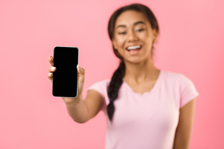 Mockup for advertisement. Happy girl showing blank screen smartphone, pink background