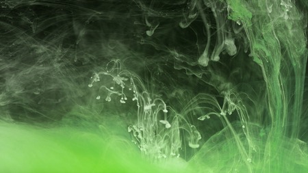 Green stains underwater on black background.. Abstract background concept