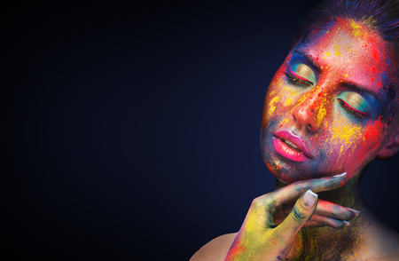 Holi colors festival. Young sensual woman with colorful powder art bodypaint on black studio background, empty spaceの写真素材