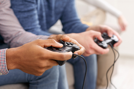 Men playing video games, having fun at home, closeup
