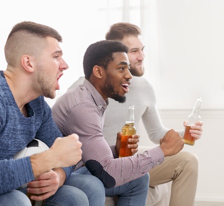 Men watching football, cheering for favourite team at home, crop