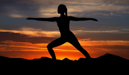 Silhouette of woman in warrior yoga pose at sunset. Sunset yoga conceptの写真素材