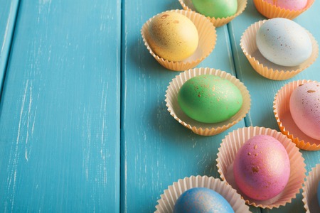 Colorful easter eggs on blue rustic wooden background. Mockup for greeting card to spring holiday,...