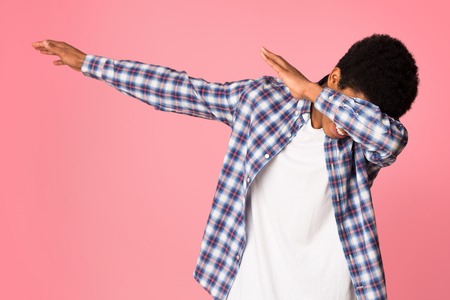 Black guy making dab gesture, having fun on pink studio background