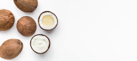 Whole coconuts, coco oil and water in halves of coconut on white background top view, copy space....