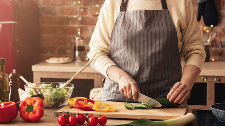 Vegetarian lifestyle in senior age. Mature woman cooking fresh vegetable salad in kitchen, panorama,...