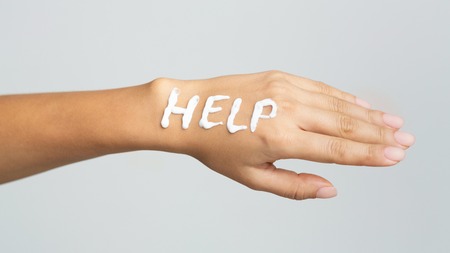 Painful dry skin. Word help written with cream on female hand