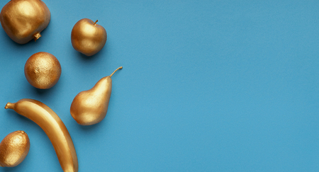 Golden fruits collage on blue background, top view, copy space. Gold and blue conceptの写真素材