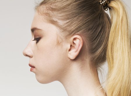 Portrait of young upset blonde millennial woman with ponytail, close upの写真素材