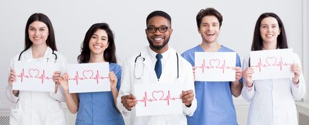 Cardiology concept. Doctors holding papers with cadiograms of heartbeat, grey background