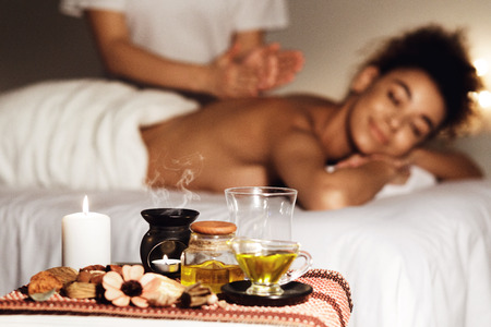 Aroma spa. Woman enjoying massage in luxury spa with candles on foregroundの写真素材