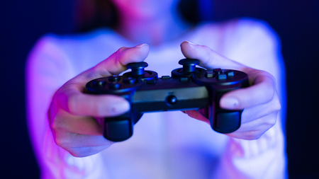 Gamer Concept. Girl holding gamepad, neon blue and pink light, closeupの写真素材