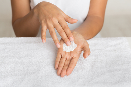 Skin nutrition. Girl spreading nourishing cream on palm against towelの写真素材
