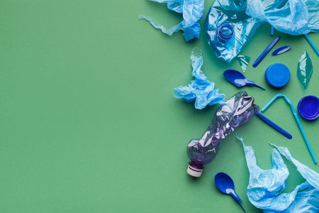 Plastic trash on green background, top view, copy space. Stop plastic pollution concept