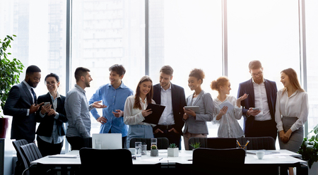 Business people standing against window, discussing work during break