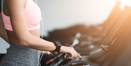 Adjusting speed. Woman training on treadmill, doing cardio workout in gym, crop