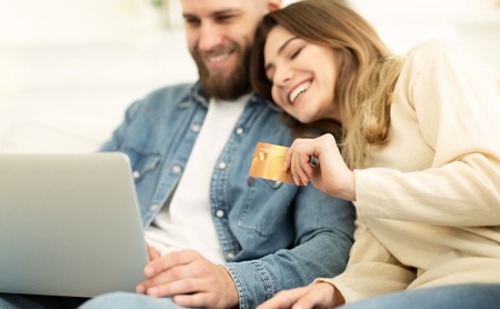 Online Shopping. Happy Couple Using Laptop And Credit Card, Resting At Homeの写真素材