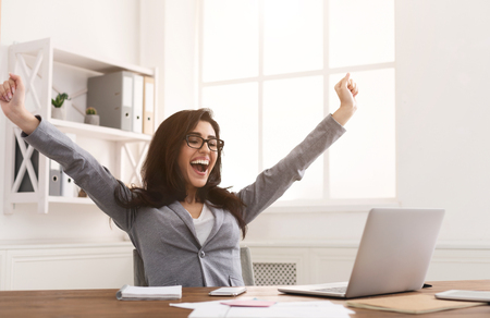 Yes! Happy Businesswoman Triumphing With Raised Hands At Workplaceの写真素材