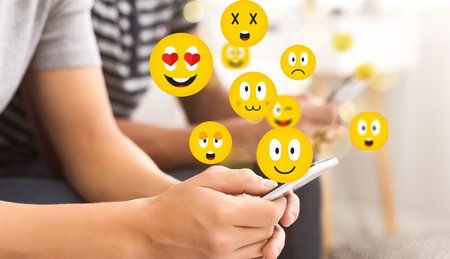Social concept. Teen guy using smartphone sending emojis, chatting in social networksの写真素材