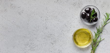 Olive oil, fresh black olives and rosemary sprig on concrete background, top view, copy spaceの写真素材