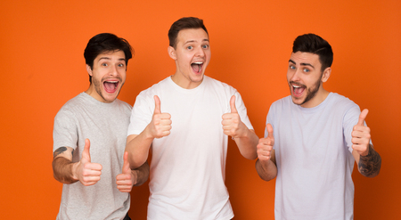 We Recommend! Happy Mates Showing Thumbs Up Over Orange Background