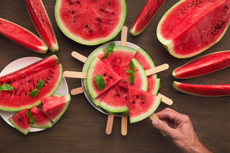 Natural summer snack. Man taking watermelon ice cream from plate, top viewの写真素材