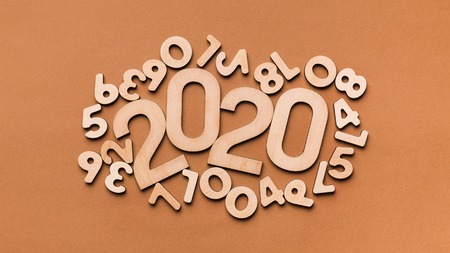 2020 year rounded by disordered wooden numbers and letters on brown background, copy space