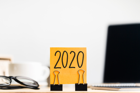 2020 orange sticker with two clips on workplace background, concept, copy space