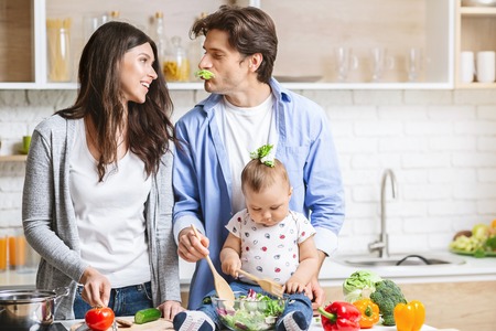 Young loving couple parents with their little baby son cooking in kitchen.の写真素材