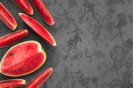 Summer cuisine. Ripe red cut watermelon on grey concrete background, free spaceの写真素材