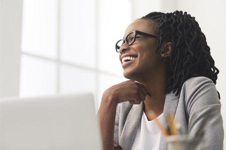 Smiling Afro Business Woman Sitting On Workplace, Looking Asideの写真素材