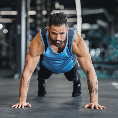 Sport motivation. Muscular man exercising push ups in gym, closeupの写真素材