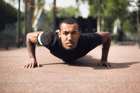 African Fit Man Doing Push-Ups In Park, Looking At Cameraの写真素材