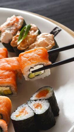 Eating salmon roll sushi in japanese restaurant for lunch, vertical panoramaの写真素材