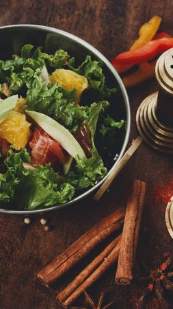 Fresh fruit and vegetable salad in copper bowl with cinamon stick on wood background, vertical panoramaの写真素材
