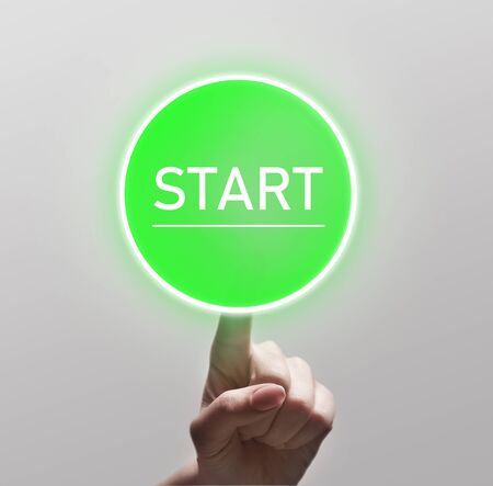 Finger touching green start button on light background, copy spaceの写真素材