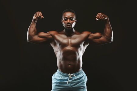 Strong man. African athlete flexing muscles, showing muscular hands and shoulders