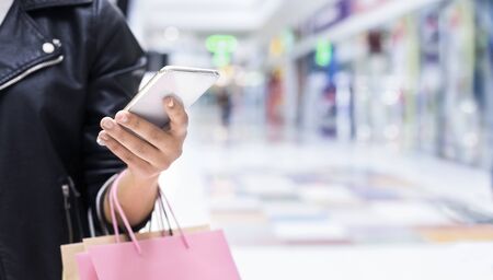 Shopping and Cashback concept, Unrecognizable woman with smartphone at mall background, panorama, copy spaceの写真素材