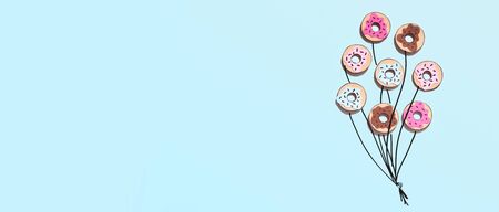 Creative food minimalism. Donuts in shape of balloons on blue summer background, panorama, copy...