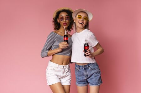 KHARKIV, UKRAINE - April 01, 2019: Multiethnic girlfriends enjoying Coca-Cola Classic with straw on...