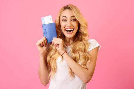 Excited Woman Holding Tickets And Passport Over Pink Backgroundの写真素材