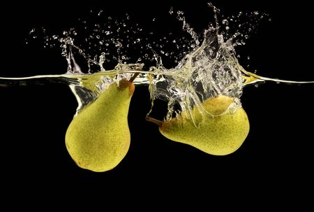 Green fresh pears with clear water splash and drops, black backgroundの写真素材
