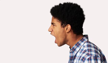 Furious Afro Guy Shouting and Looking at Copy Space over Light Background, Side View