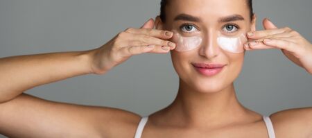 Woman with Collagen Pads under her Eyes on Grey Background, Panoramaの写真素材