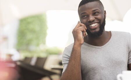 Close up portrait of african american guy talking by phone and happily smiling, panorama, free space