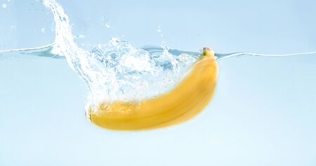 Banana falling under water with big splash, blue backgroundの写真素材