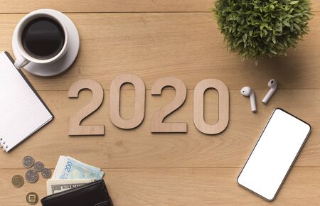 2020 concept. Cellphone with blank screen and wooden text on office background, panorama, copy spaceの写真素材