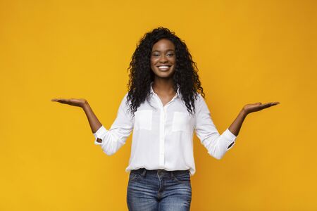 Make right choice. Positive african girl comparing variants, making scales with his empty hands,...